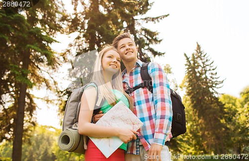 Image of smiling couple with map and backpack in nature