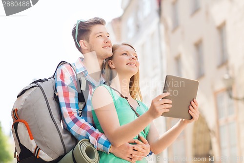 Image of smiling couple with tablet pc and backpack in city