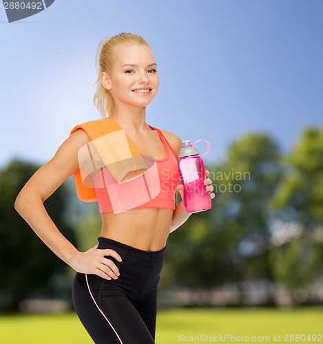 Image of smiling sporty woman with water bottle and towel