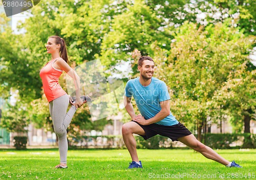 Image of smiling couple stretching outdoors