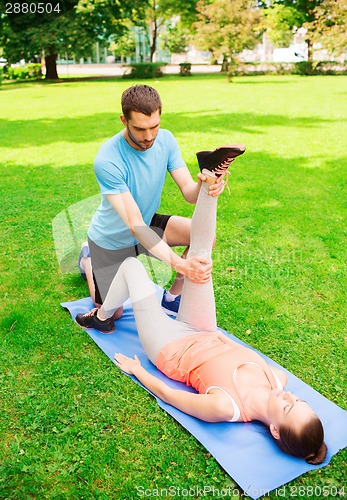 Image of serious couple stretching outdoors