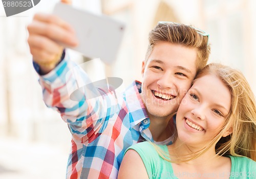 Image of smiling couple with smartphone in city