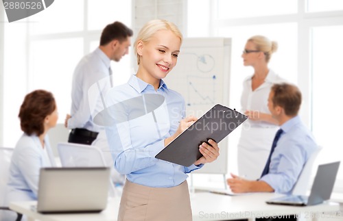 Image of smiling businesswoman with clipboard and pen