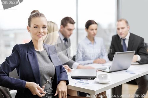 Image of businesswoman with glasses with team on the back