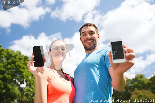 Image of two smiling people with smartphones outdoors