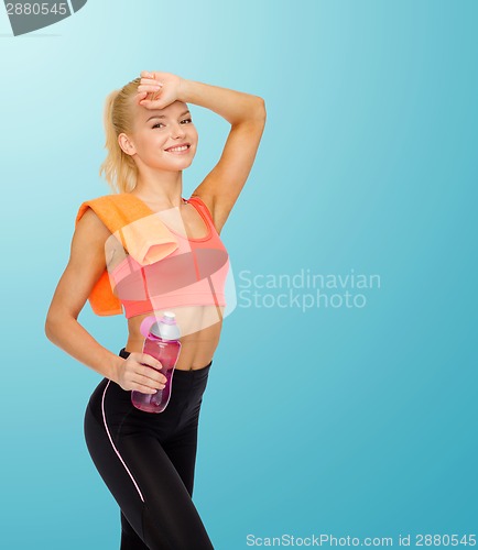 Image of smiling sporty woman with towel and water bottle