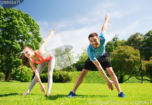 Image of smiling couple stretching outdoors