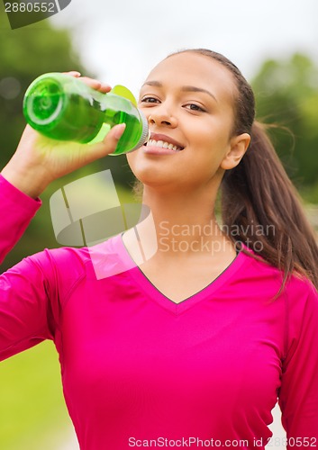 Image of smiling woman drinking from bottle