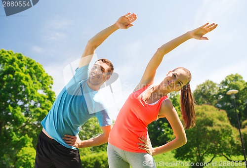 Image of smiling couple stretching outdoors