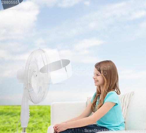 Image of smiling little girl with big fan at home