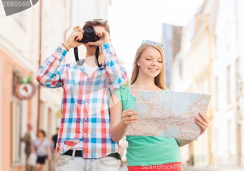 Image of smiling couple with map and photo camera in city