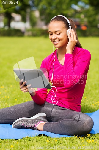 Image of smiling woman with tablet pc outdoors