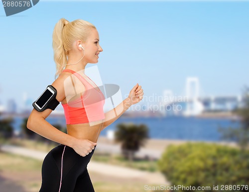 Image of sporty woman running with smartphone and earphones