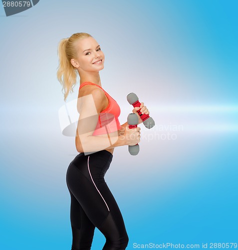 Image of smiling beautiful sporty woman with dumbbells