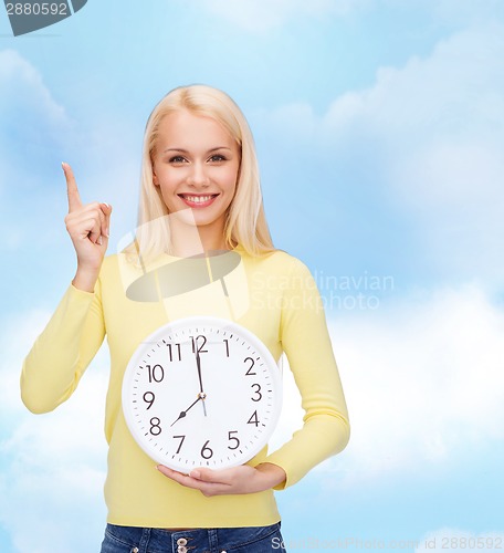 Image of student with wall clock and finger up