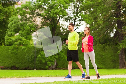 Image of smiling couple running outdoors