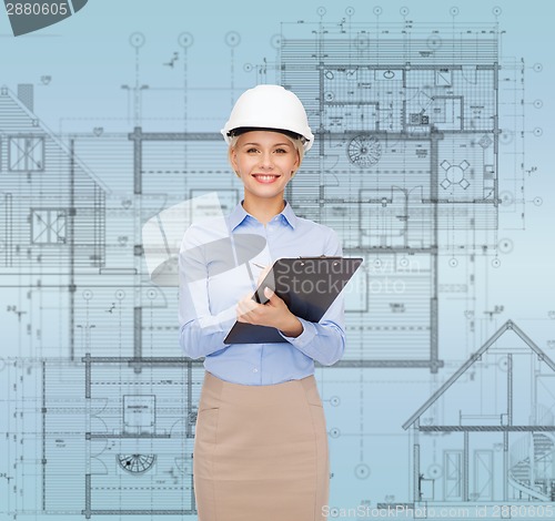 Image of smiling businesswoman in helmet with clipboard