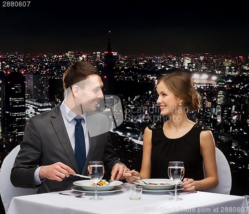 Image of smiling couple eating main course at restaurant