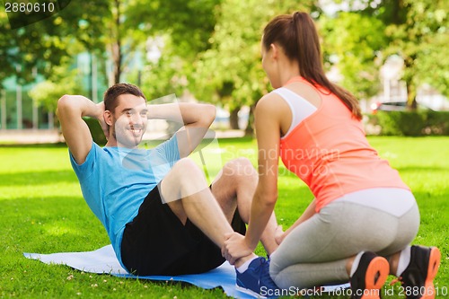 Image of smiling man doing exercises on mat outdoors