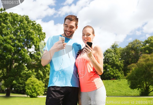 Image of two smiling people with smartphones outdoors