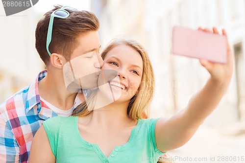 Image of smiling couple with smartphone in city