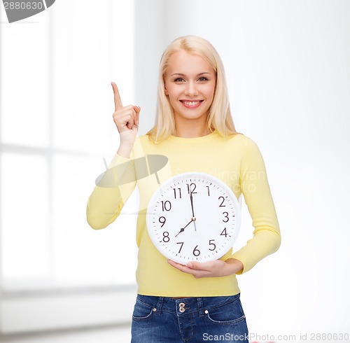 Image of student with wall clock and finger up