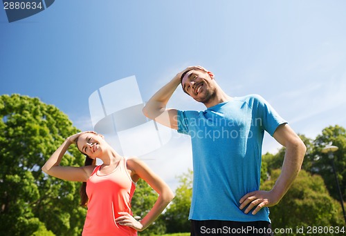 Image of smiling couple stretching outdoors