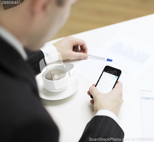 Image of businessman with smartphone reading news