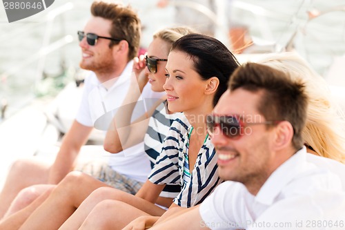 Image of smiling friends sitting on yacht deck