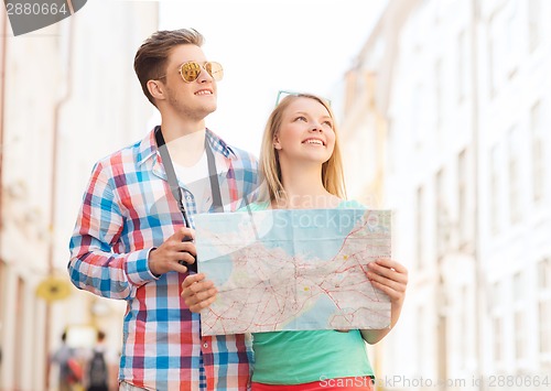 Image of smiling couple with map and photo camera in city