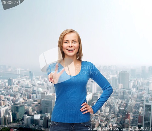 Image of smiling teenage girl showing v-sign with hand