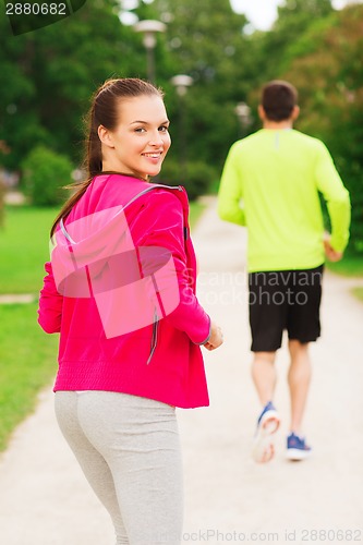 Image of smiling couple running outdoors
