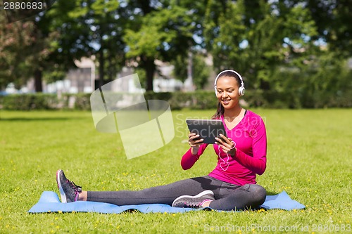 Image of smiling woman with tablet pc outdoors