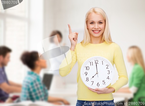 Image of student with wall clock and finger up