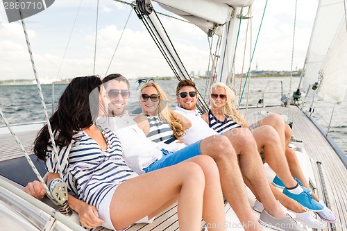 Image of smiling friends sitting on yacht deck