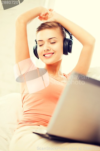 Image of woman with headphones and laptop at home
