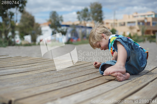 Image of Boy playing on a wooden walkway on the beach