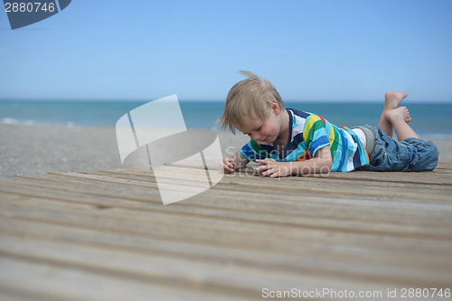 Image of Boy laying down on a wooden walkway on the beach