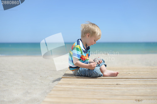 Image of Boy sitting on a wooden walkway on the beach