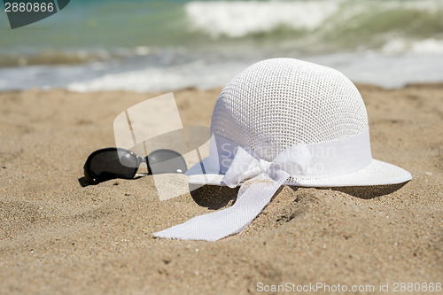 Image of Wicker white hat and sunglasses on the beach