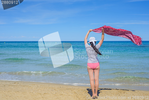 Image of Young woman holding a fabric on windy beach