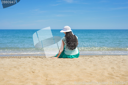 Image of Brunette female sitting alone on the beach