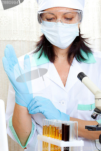 Image of doctor looking at a test tube of yellow solution and putting on 