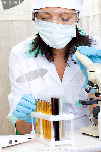 Image of scientist in laboratory analyzing yellow liquid in test tube