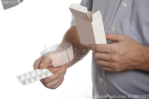 Image of Man in a blue shirt takes pills