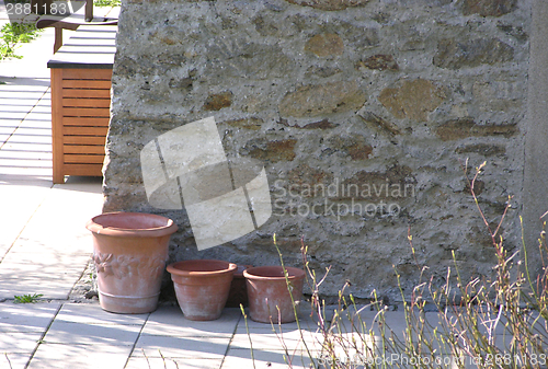 Image of Three  plant pots in front of a stone wall