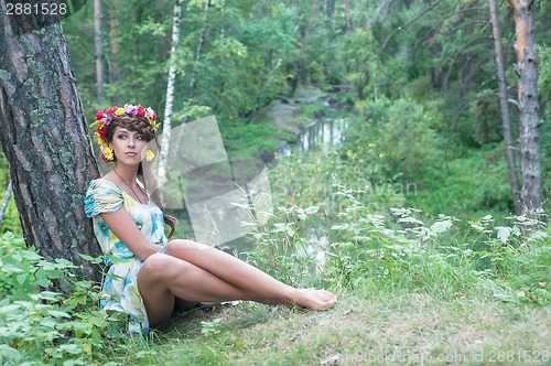 Image of Beautiful woman with flower wreath near stream