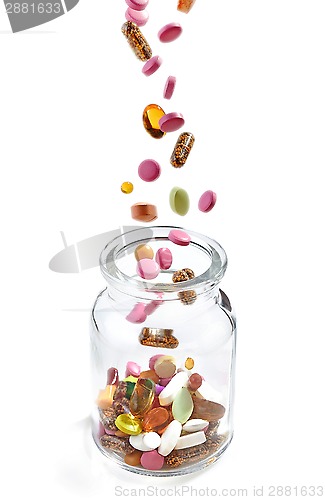 Image of various medical pills falling into jar