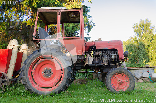 Image of close up of rural tractor with red wheel in garden 
