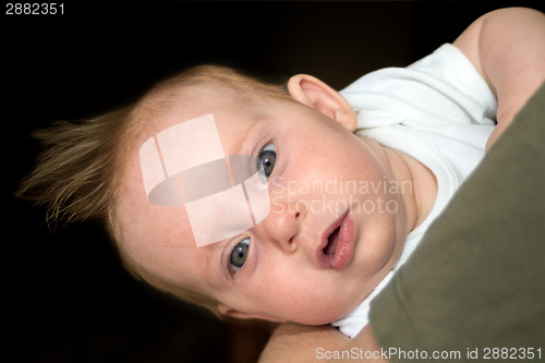 Image of An almost four month old baby girl on daddy's arm